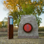 A rock with painting and a rust colored post